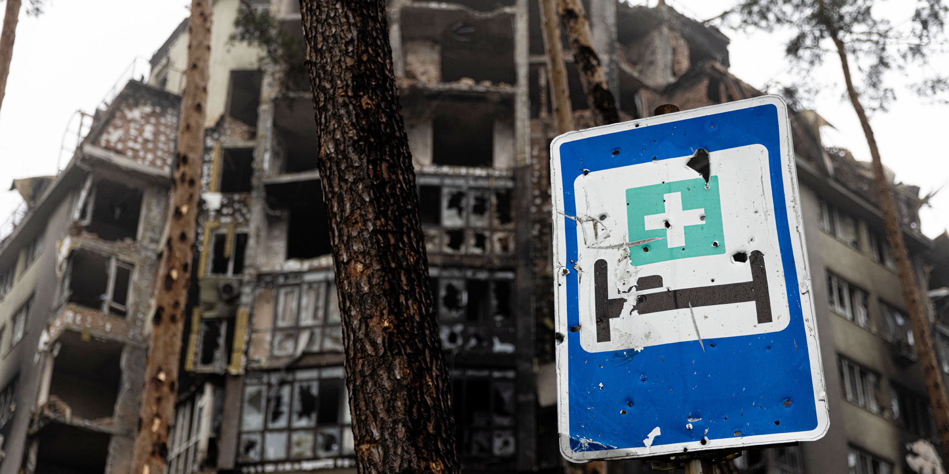 Zerstörte Gebäude und ein Schild, das auf ein Krankenhaus hinweist.
