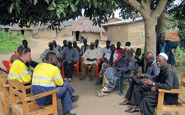 Quelque part en Guinée : réunis sous un cadre, les cadres d’une entreprise d’extraction minière discutent de l’impact de leurs activités avec les représentants d’un village.