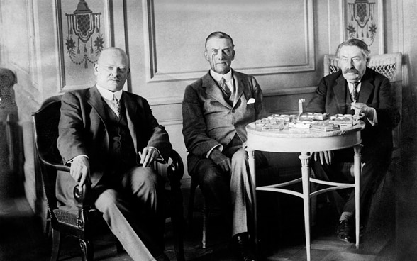 Black and white photograph of Gustav Stresemann, Austen Chamberlain and Aristide Briand, sitting next to each other at a table.