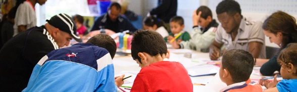 People sitting around a table reading and writing.