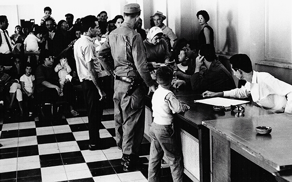 People wait at a counter in a hall in Cuba.