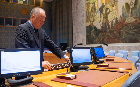 A man places the wooden plaque labelled "Switzerland" on the horseshoe-shaped table at Switzerland's place in the UN Security Council.