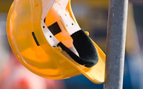 Casque de protection jaune suspendu à un échafaudage de chantier.