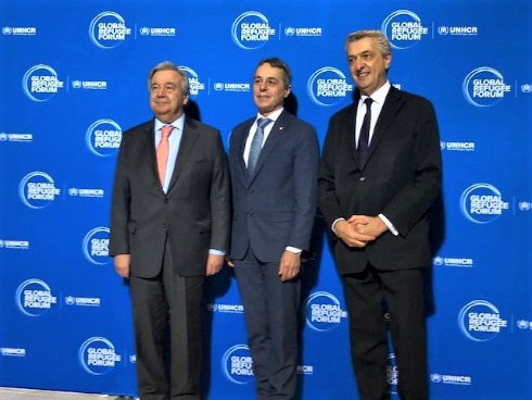 Trois homme devant un panneau bleu - Forum global pour les réfugiés