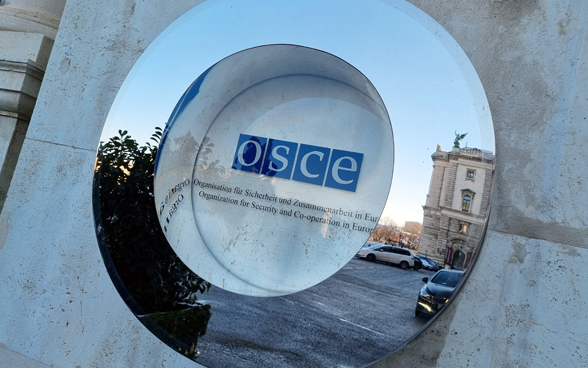 Il logo dell'OSCE sul muro di una casa dietro un vetro.