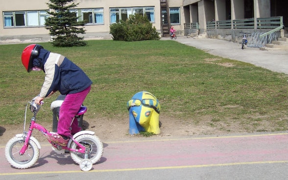 enfant faisant du vélo devant le bâtiment scolaire de Rakvere