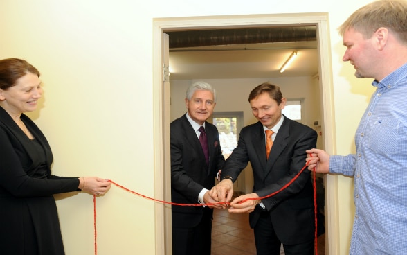 Der Schweizer Botschafter (links) durchtrennt am 16. Oktober 2014 zusammen mit dem Vorstandsvorsitzenden von ALTUM das rote Band zur Einweihung der neuen Küche.