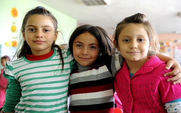 Three young girls standing together and looking into the camera.