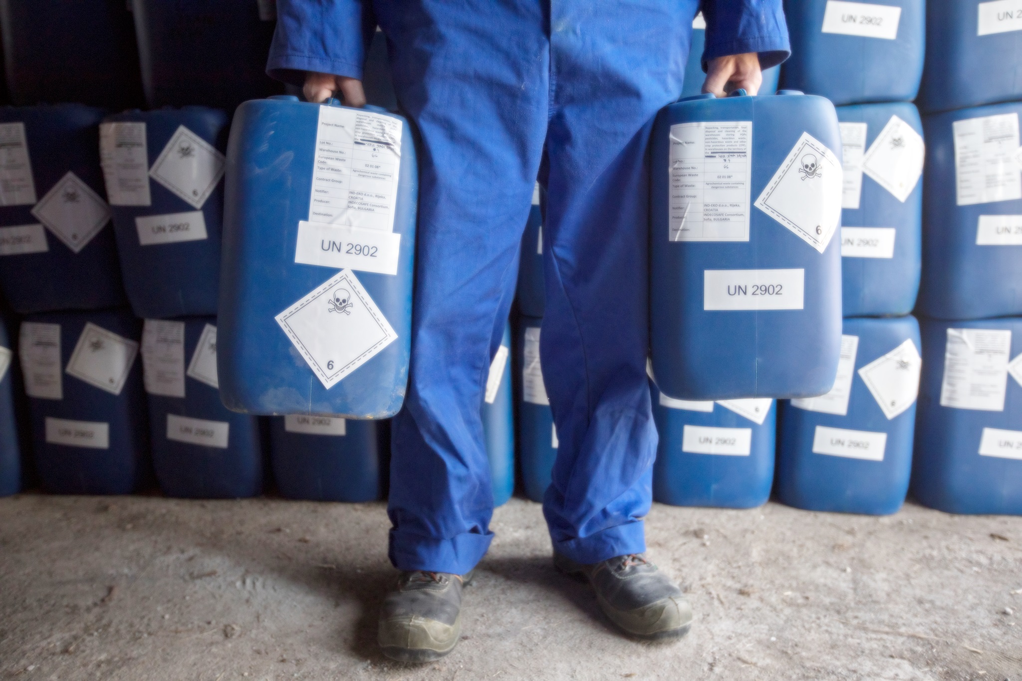 Man holds two receptacles for pesticides.