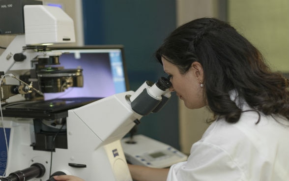 Eine Frau arbeitet im Labor an einem Mikroskop.