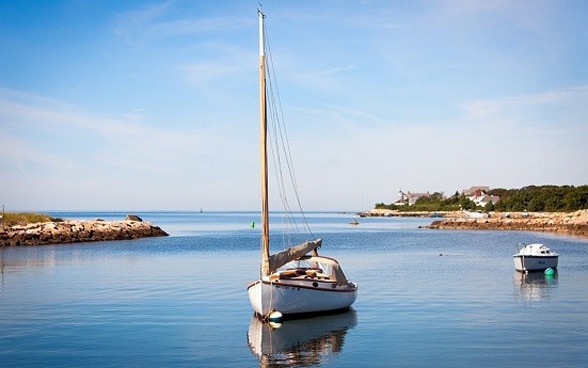 Una piccola imbarcazione ormeggiata a una boa vicino alla costa.